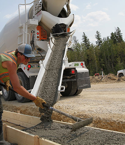 An image of a concrete worker raking concrete in forms.