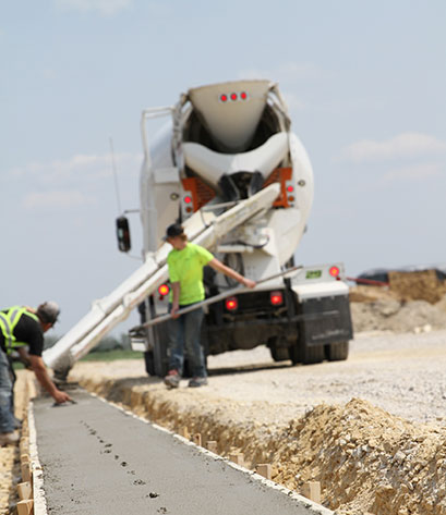 An image of a concrete worker raking concrete in forms.