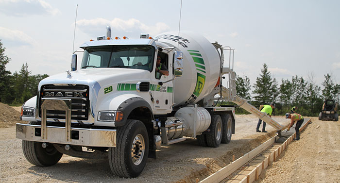 An image of a concrete truck pouring ready-mix concrete into forms.